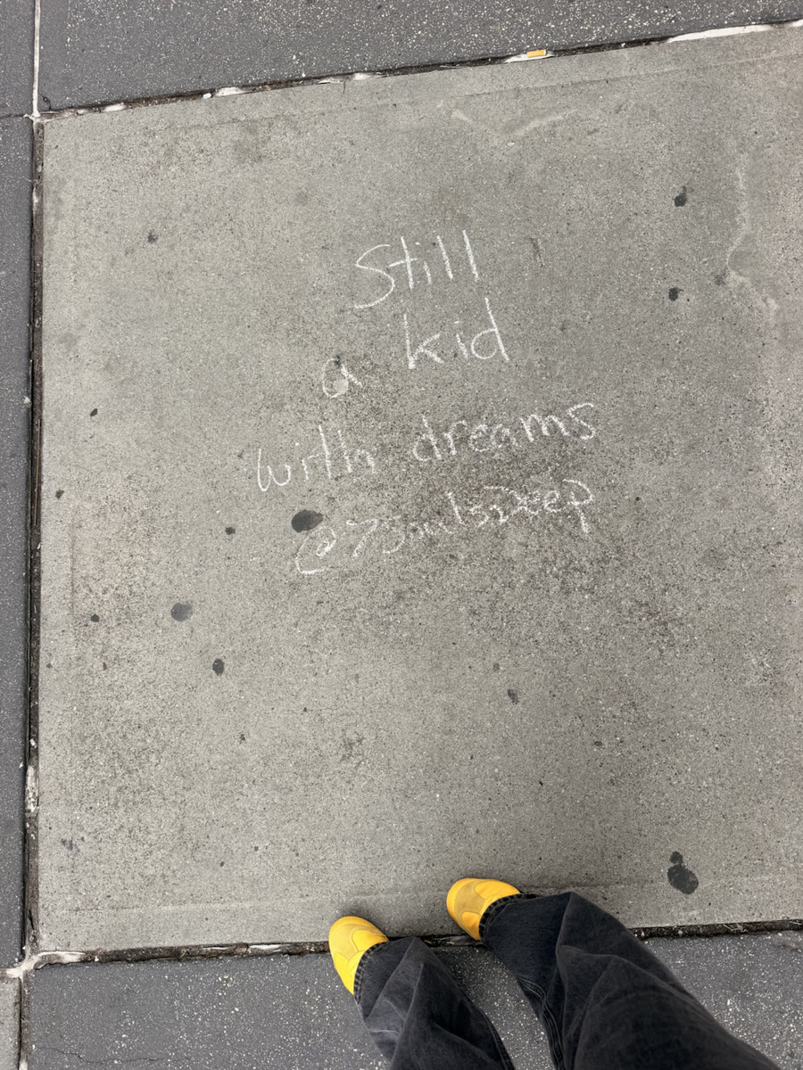 A sidewalk note reading Still a kid with dreams